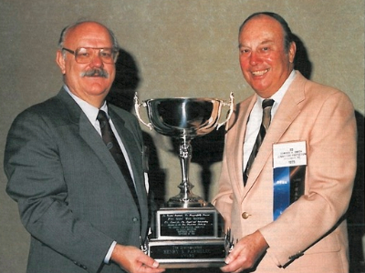 Two men, Ron Coleman and Ed Smith holding award